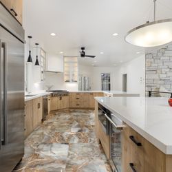 AGC Home Remodeling - Modern kitchen with flat-panel cabinets, high-end appliances, pendant lights, and multicolor marble floors in Austin, TX