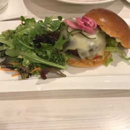 Beef burger with cheese and a side of salad.