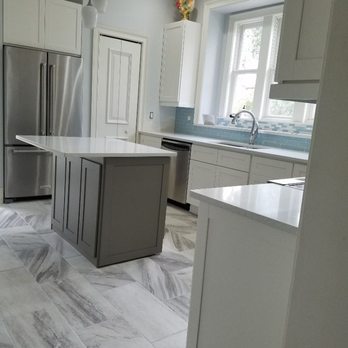 Proper Renovations - a kitchen with marble flooring and stainless steel appliances - Handyman Near Me - St Augustine, Florida