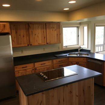 Level Up Builders - a kitchen with wood cabinets and a black countertop - General Contractors Near Me Level Up Builders - a kitchen with wood cabinets and a black countertop - General Contractors Near Me