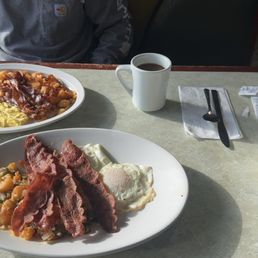 Breakfast was amazing. Everything seasoned perfectly. Customer service was great. Not a buys diner had lots of parking available - A breakfast setting at a diner with two plates of food, coffee, and tea on a table, with utensils and condiments.