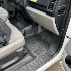 Passenger side footwell and seat filled with dirt and mud residue from the workers just wiping the weather mats down.