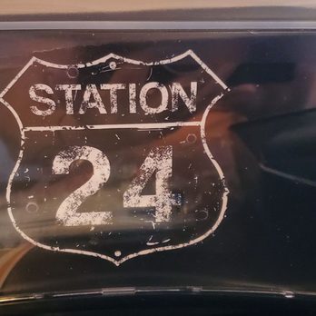 Station 24 - Logo - A sign displaying 'Station 24' in a distressed style, mounted inside a restaurant or diner setting. - American Near Me - Flat Rock, Michigan