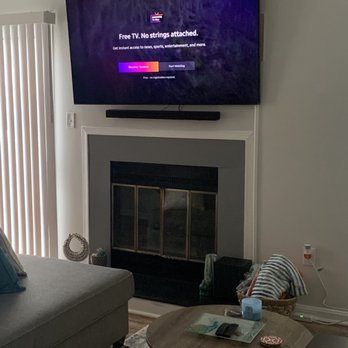 Level Up Installs - A living room features a wall-mounted TV above a fireplace, with a sofa, coffee table, and various small items visible. - Security Systems Near Me - Capitol Heights, Maryland