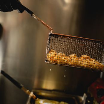 La Cruda Seafood - a person holding a frying basket over a frying pan - Seafood Near Me - San Luis, Arizona