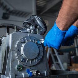 Mega Truck Trailer - Close-up of a heavy-duty truck transmission component being serviced with a wrench and blue protective gloves, highlighting m...