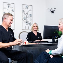 Dr. Ronan and patient care coordinator Brette discussing implants with a patient.