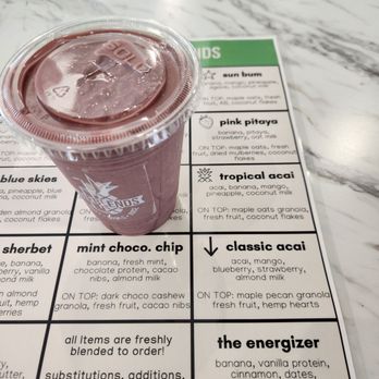 BeneBlends - A purple smoothie in a clear plastic cup with a sealed lid is placed on a marble table next to a menu listing smoothie flavors. - Juice Bars & Smoothies Near Me - Madison, Wisconsin