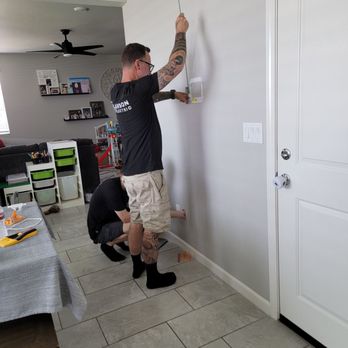 Larson Electric - Matt and son fishing the power cord through the drywall. - Electricians Near Me