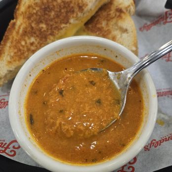 Friendly's - A bowl of Indian curry with a spoon, accompanied by toasted bread slices, on a tray with branded paper. - Ice Cream & Frozen Yogurt Near Me - Auburn, Massachusetts