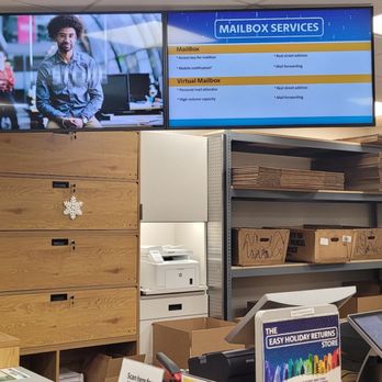 The UPS Store - Main counter - Interior of a postal or shipping store featuring mailboxes, shelving with packages, a digital screen displaying mailbox services, and a checkout counter. - Shipping Centers Near Me - Reading, Pennsylvania