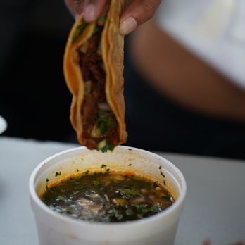 Birria Catrina - a person holding a sandwich over a bowl of soup - Mexican Near Me - Toronto, Ontario