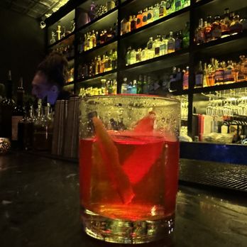 Gin & Reel - a glass of gin and a man in the background - Speakeasies Near Me - Phoenix, Arizona Gin & Reel - a glass of gin and a man in the background - Speakeasies Near Me - Phoenix, Arizona
