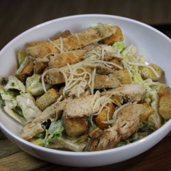 Stars and Strikes - A freshly grilled chicken breast atop chopped romaine lettuce, tossed with parmesan cheese, croutons, and caesar dressing