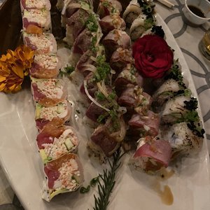 Photo of Aburi Sushi - San Diego, CA, United States. Lollipop Roll, Surf and Turf Roll, HK Scallop Roll, Aburi Roll (with little flowers as a decor)