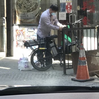 Orchid Garden - a man sitting on a bike in front of a store - Barbeque Near Me - Brooklyn, New York