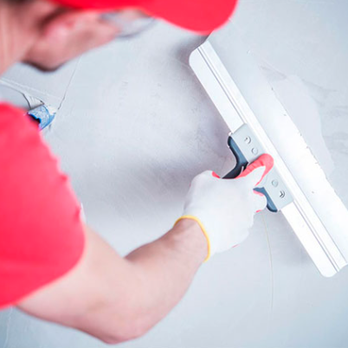 CMC Drywall - a man using a sqing tool on a wall - Drywall Installation & Repair Near Me