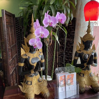 Siri Thai - a pair of statues with orchids in the background - Thai Near Me - Portland, Oregon Siri Thai - a pair of statues with orchids in the background - Thai Near Me - Portland, Oregon