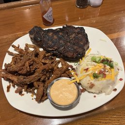 Ribeye steak with loaded mashed potatoes and onion petals. Ribeye steak with loaded mashed potatoes and onion petals.