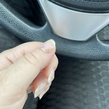 Lz Nails - A hand with long, damaged nails is positioned near a car's steering wheel, with the interior of the vehicle visible. - Nail Salons Near Me - Manhattan, Illinois