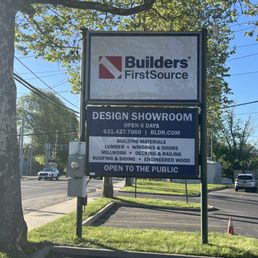 Exterior outside entrance of Builders FirstSource - A Builders FirstSource road sign listing showroom hours, contact information, and services like lumber, windows, doors, and m... - Huntington, New York Exterior outside entrance of Builders FirstSource - A Builders FirstSource road sign listing showroom hours, contact information, and services like lumber, windows, doors, and m... - Huntington, New York