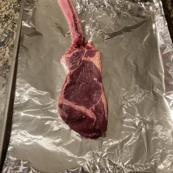 Northstar Bison - Tomahawk! - A raw, bone-in cut of red meat, possibly a steak, is laid on aluminum foil on a baking sheet, ready for cooking or preparation. - Meat Shops Near Me - Cameron, Wisconsin