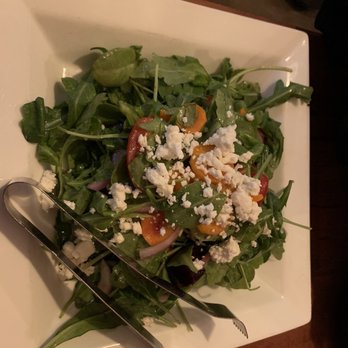 Sam's Kitchen - Garden Salad - A garden salad featuring mixed greens, cherry tomatoes, sliced red onions, and crumbled cheese served on a square white plate, with salad tongs. - Italian Near Me - Woburn, Massachusetts