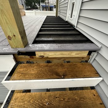 J White Construction - A construction site showing a partially built deck with wooden planks and composite decking materials, adjacent to a house with vinyl siding. - Roofing Near Me - Wilmington, Massachusetts