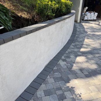 My Outdoor Builder - Custom curved retaining wall with stucco finish and concrete block cap, paired with a beautifully laid paver driveway. - Masonry/Concrete Near Me - Anaheim, California My Outdoor Builder - Custom curved retaining wall with stucco finish and concrete block cap, paired with a beautifully laid paver driveway. - Masonry/Concrete Near Me - Anaheim, California