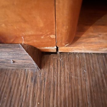 Ed's Floor & Home - Gap and mis measure . Should reach door and no space should show - A photo showing a gap at the bottom corner of a wooden cabinet, with visible misalignment and space between the cabinet and the floor. - Carpeting Near Me - Plaistow, New Hampshire