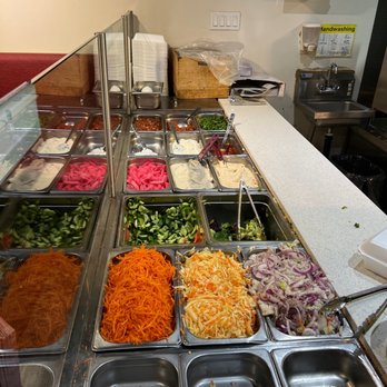 Sofra Istanbul - A salad bar featuring fresh vegetables like carrots, cucumbers, and onions, along with toppings such as pickled ginger and sauces, in a restaurant. - Mediterranean Near Me - Vaughan, Ontario