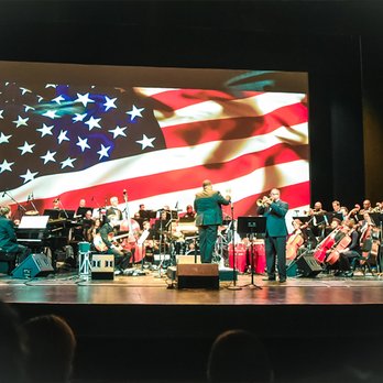 Chicago Jazz Philharmonic - a band on stage with an american flag projected on the screen - Jazz & Blues Near Me - Chicago, Illinois