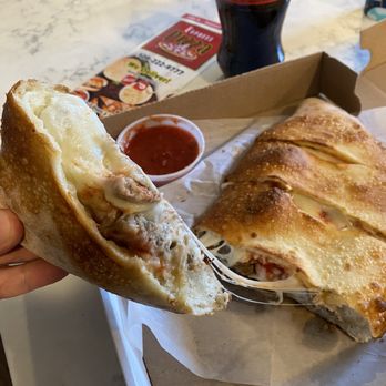 Express Pizza - a hand holding a half eaten sandwich - Pizza Near Me - Norton, Massachusetts