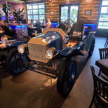 Ford's Garage Florence - A vintage-style car is used as decor inside a restaurant, featuring wooden wall accents, neon lighting, and patrons dining in the background. - Burgers Near Me - Florence, Kentucky