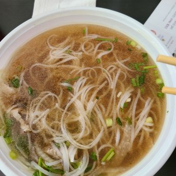 Pholicious - Beef pho soup - A bowl of beef pho soup with rice noodles, chopped green onions, and herbs in a clear broth. - Vietnamese Near Me - Ashburn, Virginia