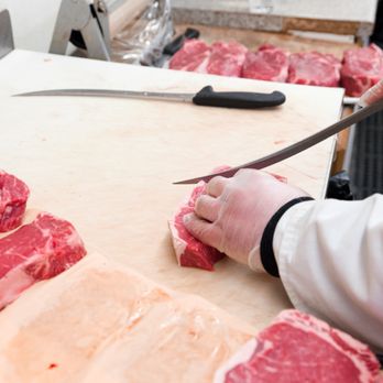 Hillside Meat Market - a person cutting raw meat on a cutting board - Meat Shops Near Me - Bronx, New York Hillside Meat Market - a person cutting raw meat on a cutting board - Meat Shops Near Me - Bronx, New York