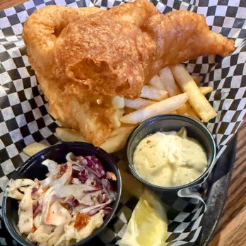 Effingbar And Grill - Fish & Chips Special - A plate of fish and chips features a large piece of battered fried fish, French fries, a small container of tartar sauce, a side of coleslaw, and a lemon wedge. The food is served on a checkered paper-lined tray, typical of casual dining or pub-style restaurants. - American Near Me - Albuquerque, New Mexico