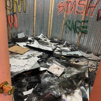 AxeZone - Axe Throwing Lounge, Naperville - A room with metal sheeting on the walls; there is broken metal and other destroyed materials all over the floor. - Axe Throwing Near Me - Naperville, Illinois