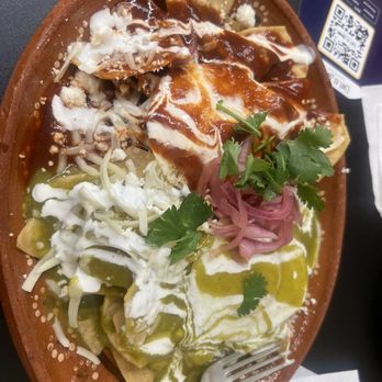 Cafe es Amor - Chilaquiles - A dish of chilaquiles served on a ceramic plate, topped with sauces, cheese, and garnishes, including cilantro and pickled onions. - Coffee & Tea Near Me - Albuquerque, New Mexico