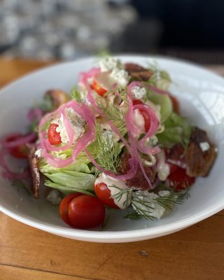 Photo of Latona Pub - Seattle, WA, US. Wedge salad with candied bacon, pickled red onion, Roma tomatoes, and dill, topped with miso blue cheese dressing