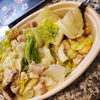 Grabbagreen - The core of the problem - A salad with lettuce, chicken pieces, croutons, and cheese in a disposable container, placed on a granite countertop. - Juice Bars & Smoothies Near Me - Killeen, Texas