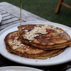 Two griddled cakes with caramelized pineapple, cherries, brown sugar, maple syrup, whipped cream