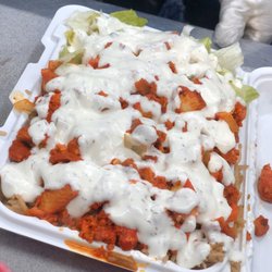 Abdul Halal Food Cart - Chicken over rice with salad , white sauce on top .