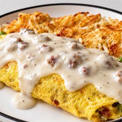 Kitchen Sink Omelet  Loaded omelet topped with creamy sausage gravy, served with crispy hash browns.