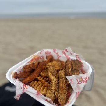 Top Tenders & Wings - a person holding a tray of food on the beach - Chicken Wings Near Me - Redondo Beach, California