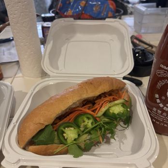 Saigon 2 - Bahn Mi - A banh mi sandwich with sliced cucumbers, carrots, cilantro, and jalapeños in a white takeout box. - Pop-Up Restaurants Near Me - Ceres, California