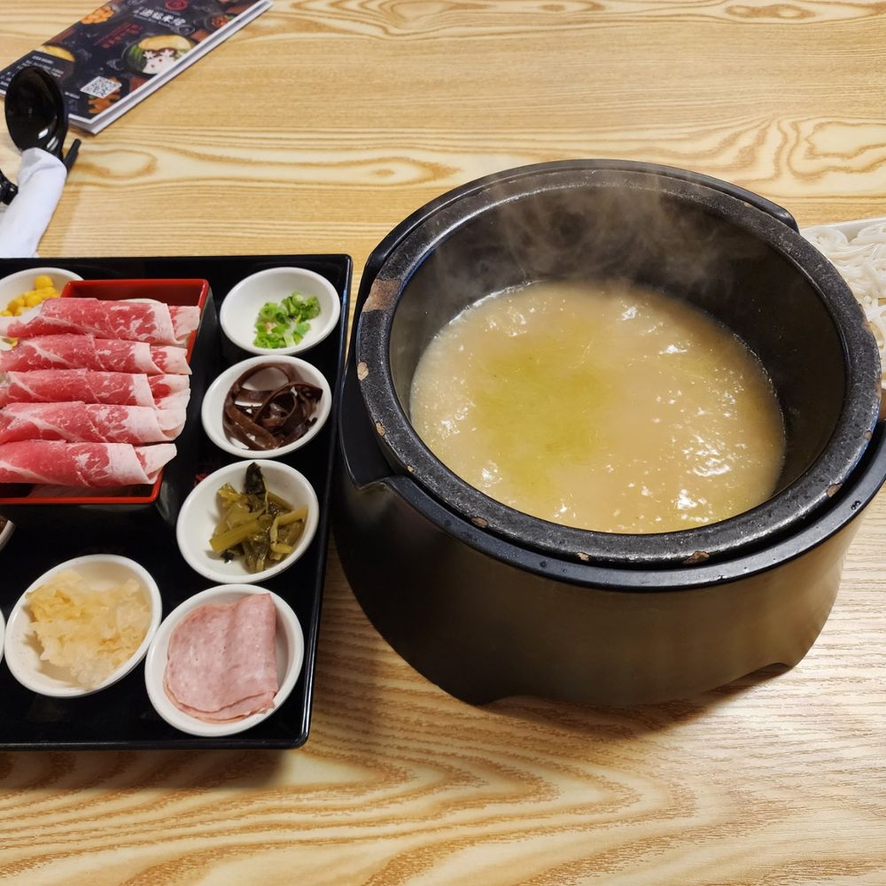 a pot of soup and bowls of meat a pot of soup and bowls of meat