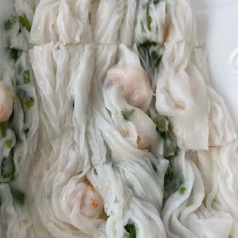 Big Fun Cafe - Shrimp Steamed Rice Roll - The image shows a close-up of steamed rice rolls filled with shrimp, topped with chopped green onions. The rice rolls are soft and slightly translucent, with visible shrimp pieces inside. The dish appears to be served with a creamy sauce, possibly on a white plate or tray. The presentation emphasizes the texture and ingredients of the traditional Cantonese steamed rice roll dish. - Cantonese Near Me - Quincy, Massachusetts