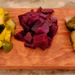 Pickle Plate - Slices of pickles, diced beets, and Brussels sprouts are arranged on a wooden serving board, likely for a tasting or appetizer.