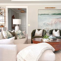 One Coast Design - A beautiful soft and neutral living room set up with a copper coffee table and an oversized painting on the rear wall. A neutral sectional